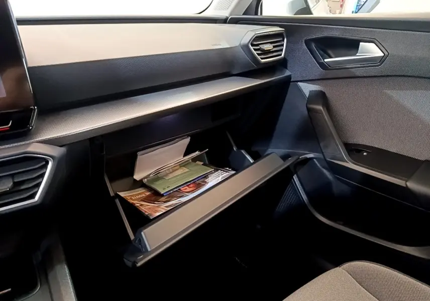 Intérieur côté passager du SEAT Leon 2023 avec boîte à gants ouverte et tableau de bord gris foncé.