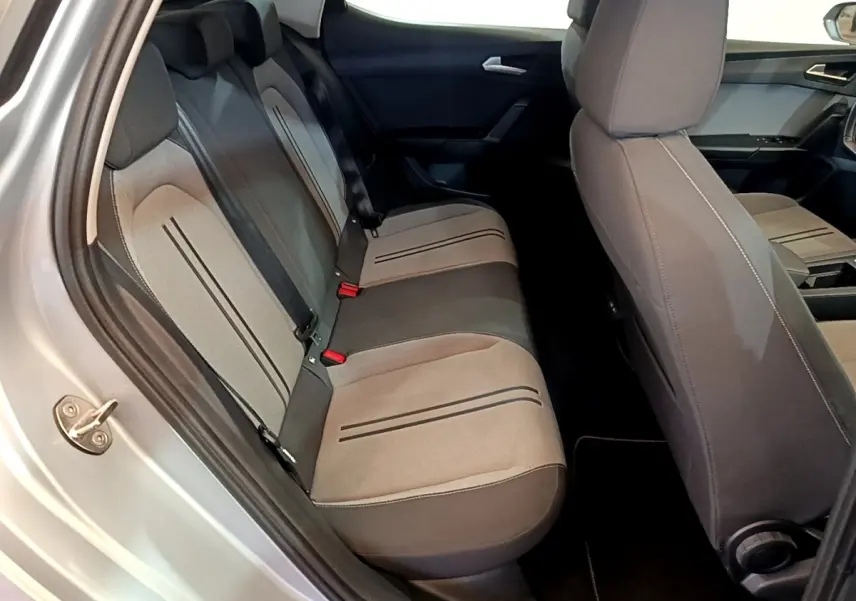 Vue intérieure côté gauche montrant la banquette arrière grise et les sièges avant du SEAT LEON 1.0 TSI 2023.
