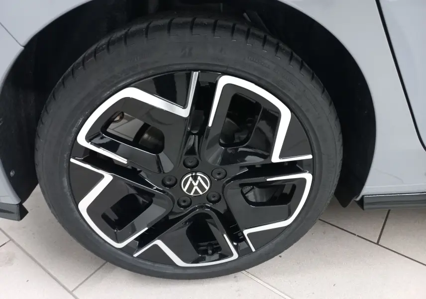 Gros plan sur la roue avant droite de la Volkswagen Golf gris lunaire, jante noire et argentée au design moderne.