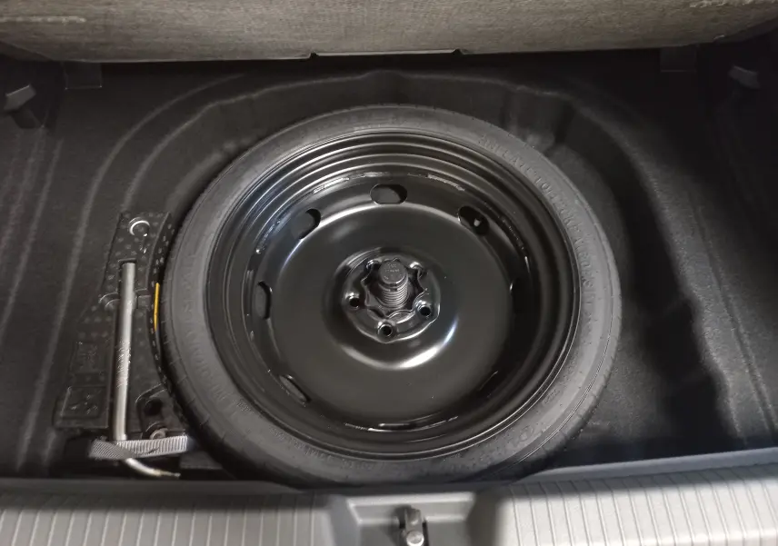 Gros plan sur la roue de secours à encombrement réduit dans le coffre d’une Volkswagen Golf gris lunaire 2026.