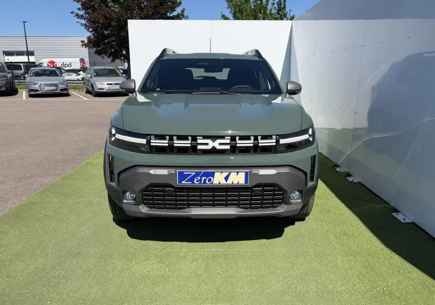 Vue de face du Dacia Duster III hybride en kaki lichen avec calandre noire et signature lumineuse LED fine.