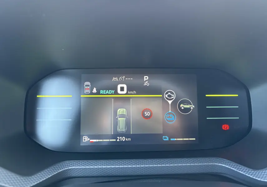 Tableau de bord digital du Dacia Duster 2026 affichant la vitesse, autonomie et alertes, vu de face en intérieur.