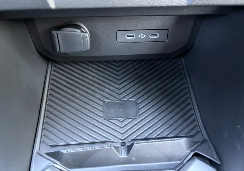 Gros plan sur la console centrale noire du Dacia Duster III 2026, montrant les prises USB type C et le chargeur à induction.