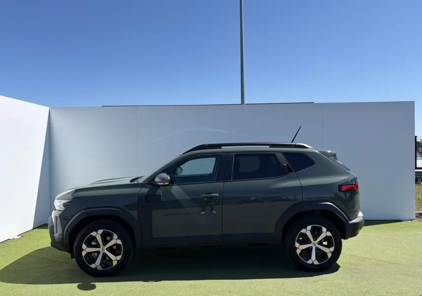 Vue de profil côté gauche du Dacia Duster III hybride 2026 en kaki lichen avec jantes alliage 18 pouces diamantées.