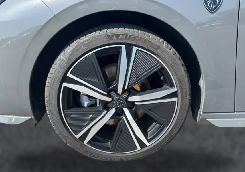 Gros plan sur la roue avant droite grise d’une Peugeot 308 1.2 hybrid 145 GT avec jante alu noire et argentée.