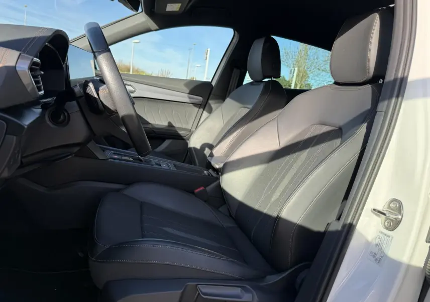 Vue intérieure côté conducteur du CUPRA Formentor blanc 2023, sièges en cuir noir avec surpiqûres contrastées.