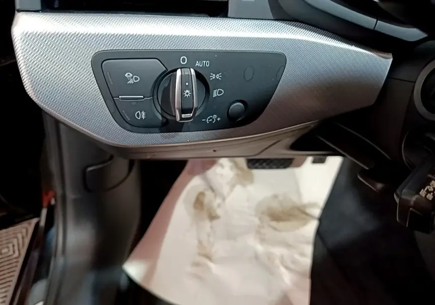 Gros plan sur la commande des phares à gauche du volant dans l'habitacle noir de l'Audi A4 40 TDI 2018.