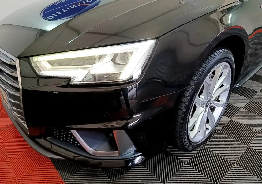 Gros plan sur l'avant droit noir d'une Audi A4 40 TDI 2018, mettant en valeur le phare LED et la jante alu.