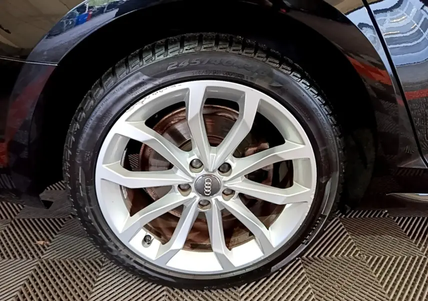 Gros plan sur la roue avant droite d’une Audi A4 noire 2018, mettant en valeur la jante alliage argentée à 10 branches.