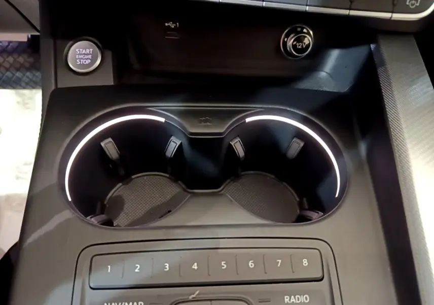 Gros plan sur la console centrale noire de l'Audi A4 40 TDI 2018, avec porte-gobelets éclairés et bouton démarrage visible.