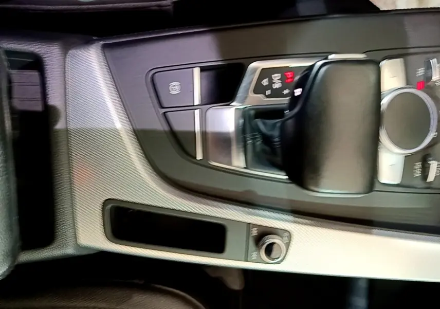 Gros plan sur la console centrale noire et argentée de l'Audi A4 40 TDI 190 Quat S tronic Design Luxe avec levier de vitesse automatique.