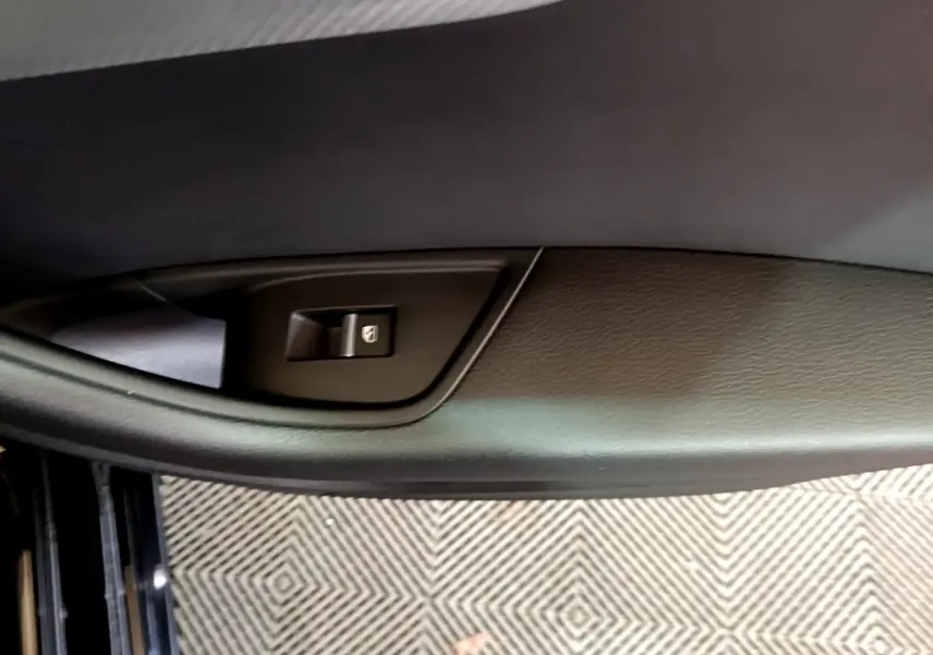 Gros plan sur la commande de lève-vitre côté conducteur d'une Audi A4 noire, intérieur cuir noir.