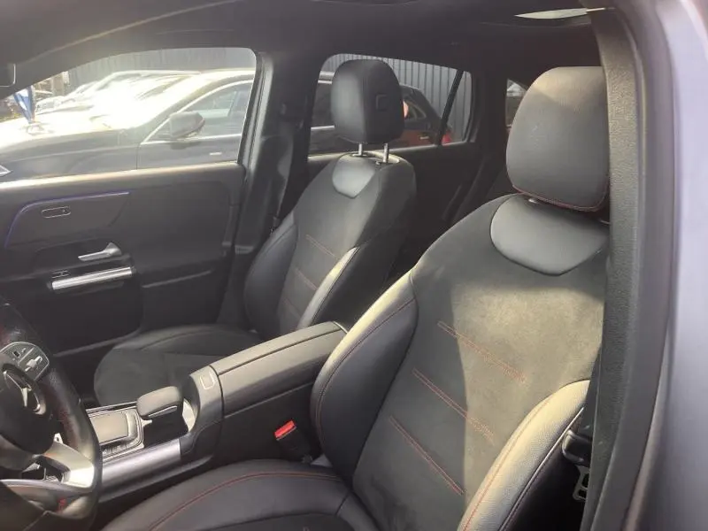 Vue intérieure côté avant droit du Mercedes GLA 200 d AMG Line 2021, sièges sport noirs avec surpiqûres rouges.