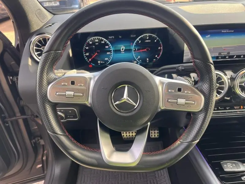 Vue intérieure centrée sur le volant cuir perforé avec surpiqûres rouges du Mercedes GLA 200 d AMG Line 2021.