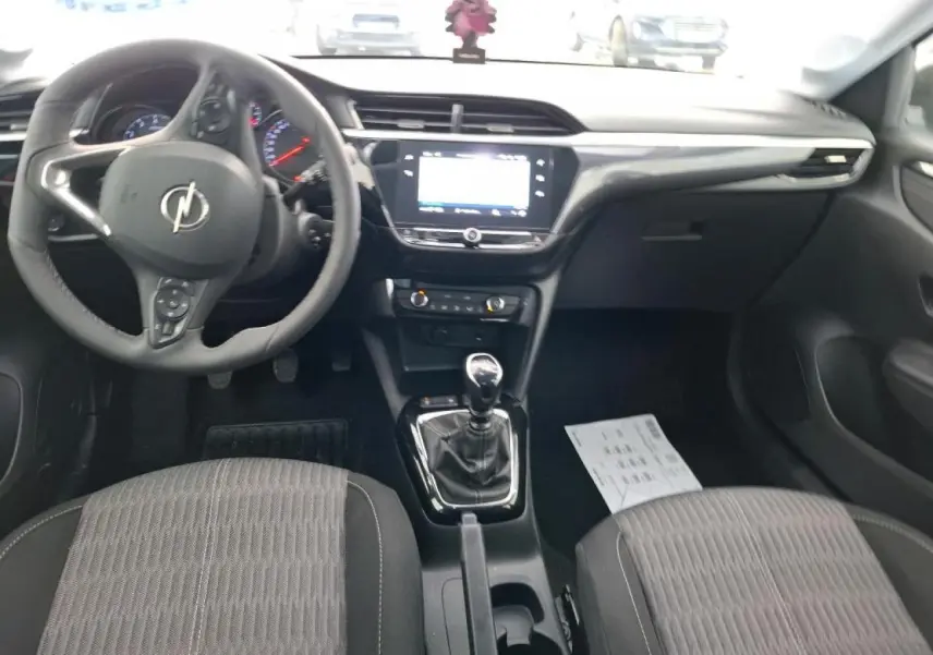 Vue intérieure avant de l’Opel Corsa 2023, tableau de bord noir avec écran tactile et levier de vitesses manuel.