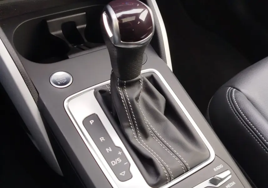 Gros plan sur le levier de vitesses automatique en cuir noir et bouton start/stop de l’Audi Q2 35 TFSI 2023.