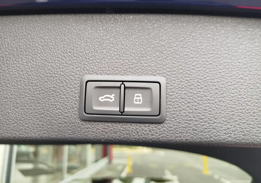 Boutons d'ouverture du coffre et de verrouillage intégrés dans la garniture intérieure du hayon d'un Audi Q2 bleu Navarre.