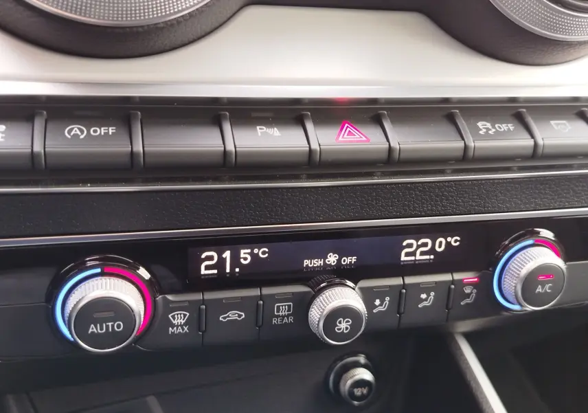 Gros plan sur la console de climatisation digitale de l'Audi Q2 35 TFSI bleu Navarre, avec réglages à 21,5°C et 22°C.