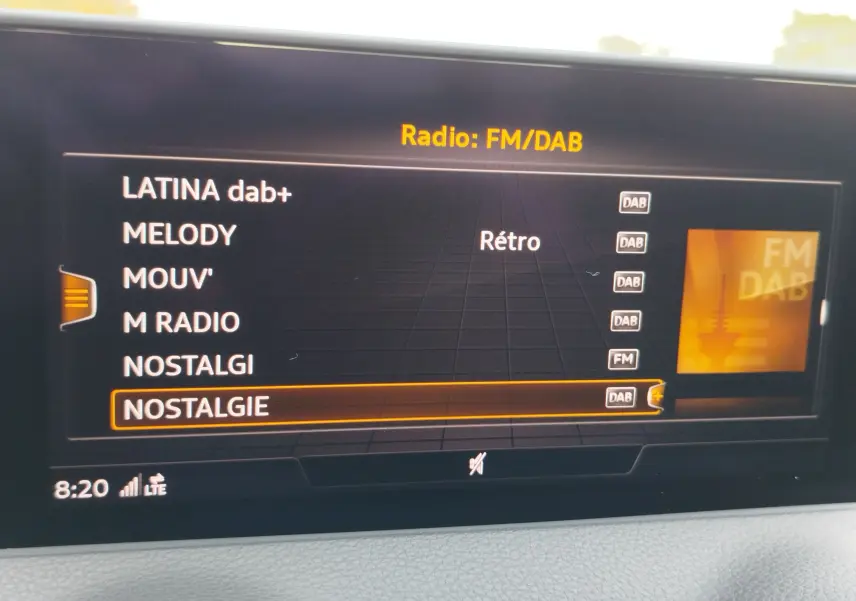 Écran multimédia de l'Audi Q2 35 TFSI 2023 affichant la liste des radios DAB/FM en intérieur gris.
