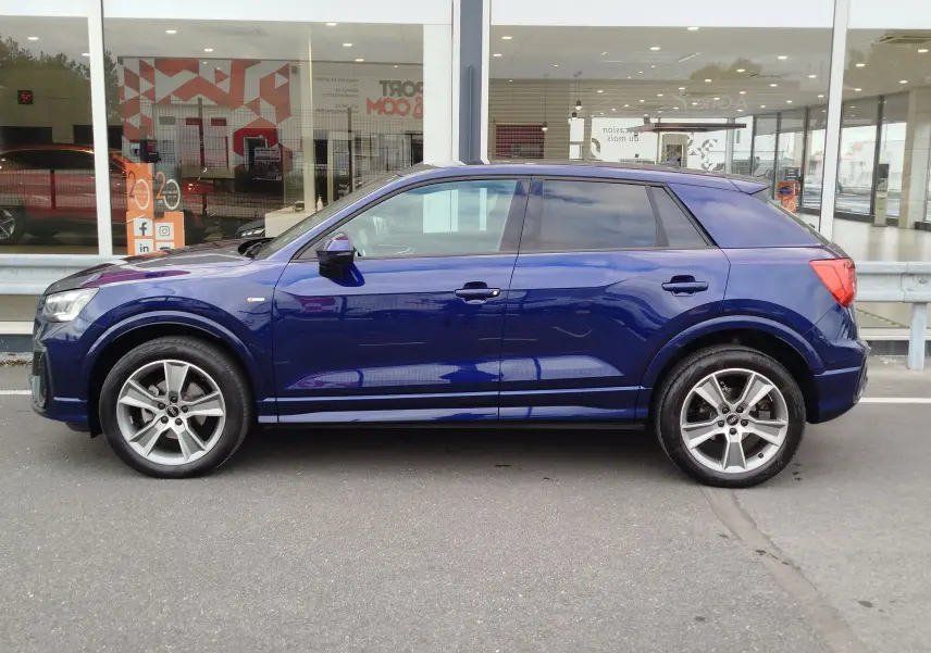 Audi Q2 bleu Navarre vue de profil côté gauche, avec jantes alliage 5 branches et toit noir contrasté.