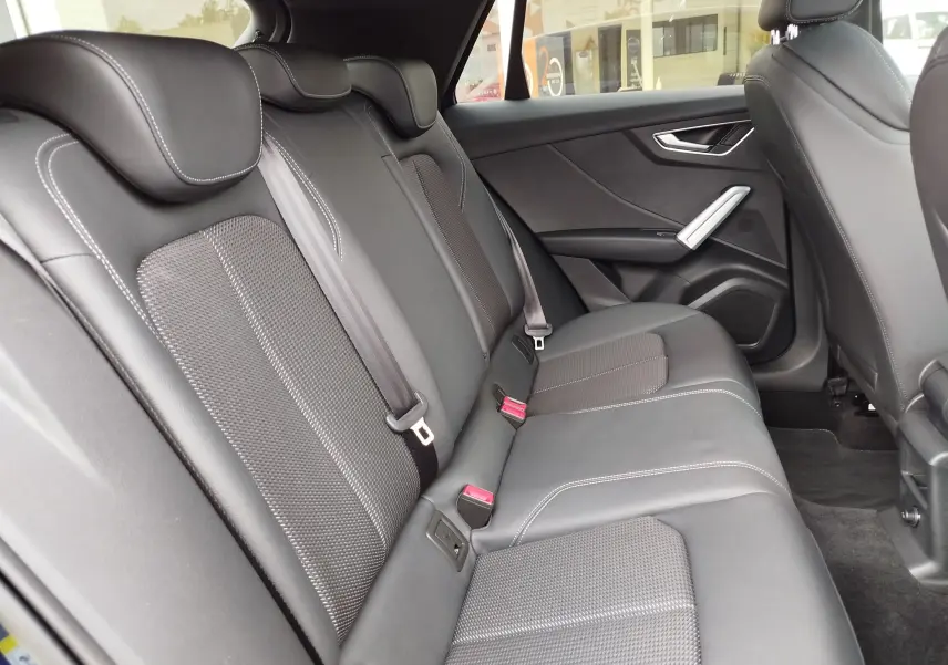 Vue latérale droite de l’habitacle arrière de l’Audi Q2 2023 avec sièges en cuir noir et surpiqûres blanches.