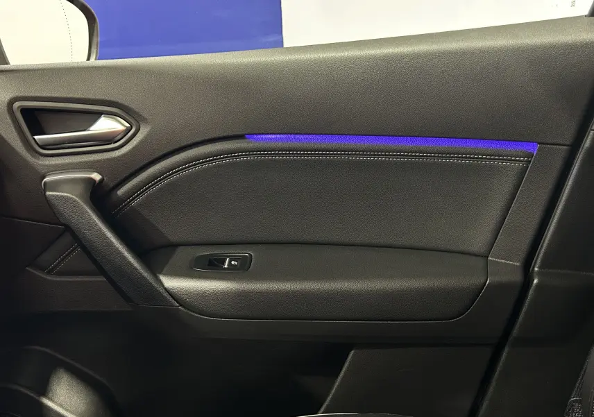 Gros plan sur la porte intérieure côté gauche du Renault Captur 2024 avec éclairage d'ambiance bleu et finition cuir noir.