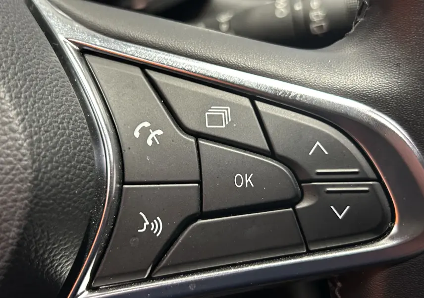 Gros plan sur les commandes au volant du Renault Captur 2024, finition TCE 90CH TECHNO, boutons noirs avec cadre chromé.