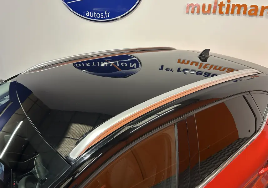 Vue en plongée du toit noir brillant et des barres de toit argentées du Renault Captur rouge flamme métallisé 2024.