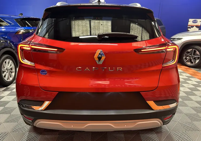 Vue arrière d'un Renault Captur rouge flamme métal 2024 avec feux LED et logo central bien visibles.