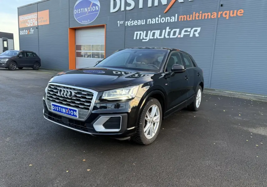 Audi Q2 noir brillant vue 3/4 avant droit avec calandre chromée et jantes argentées sur parking extérieur.