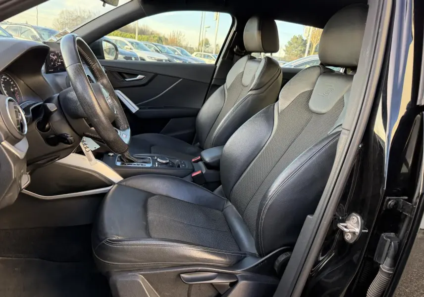 Intérieur noir de l'Audi Q2 S line 2019 vu côté conducteur, avec sièges sport en cuir et volant multifonction.