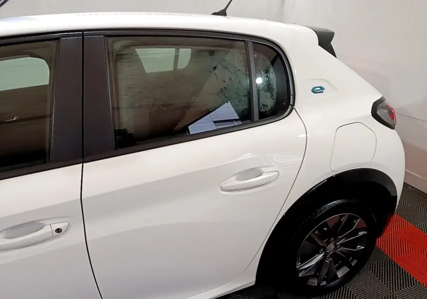 Vue côté droit arrière d'une Peugeot 208 électrique Active Business blanche avec logo "e" bleu distinctif.