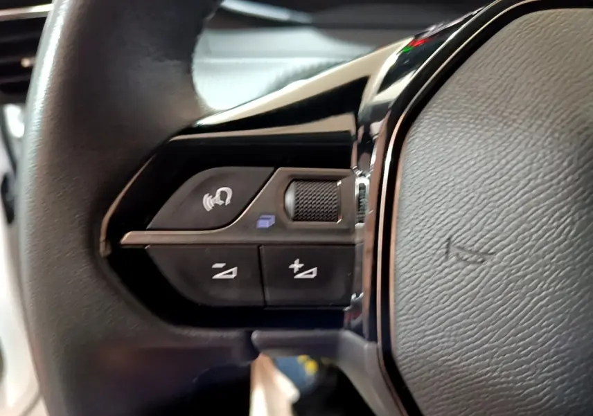 Gros plan sur les commandes gauche du volant cuir du Peugeot 208 Electrique Active Business blanc, 2021.