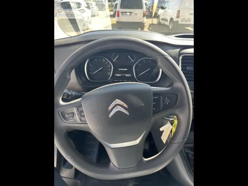 Vue intérieure centrée sur le volant noir Citroën avec tableau de bord et clés accrochées côté droit.