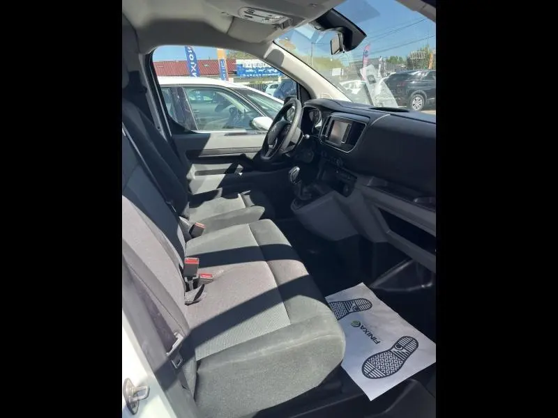 Vue intérieure côté conducteur du Citroën Jumpy blanc Banquise, montrant la banquette avant 2 places et le tableau de bord.