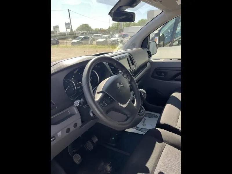 Intérieur côté conducteur du Citroën Jumpy blanc, volant multifonction, tableau de bord avec écran tactile et sièges tissu noirs.