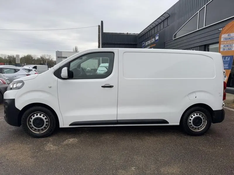 Vue de profil côté gauche d’un utilitaire Citroën Jumpy blanc Banquise avec portes arrière battantes et porte latérale coulissante droite.