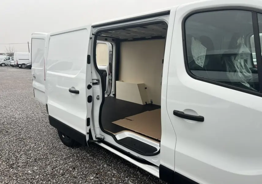 Vue latérale droite d’un utilitaire Nissan Primastar blanc 2025 avec porte coulissante ouverte montrant l’aménagement intérieur bois du Pack Cargo.