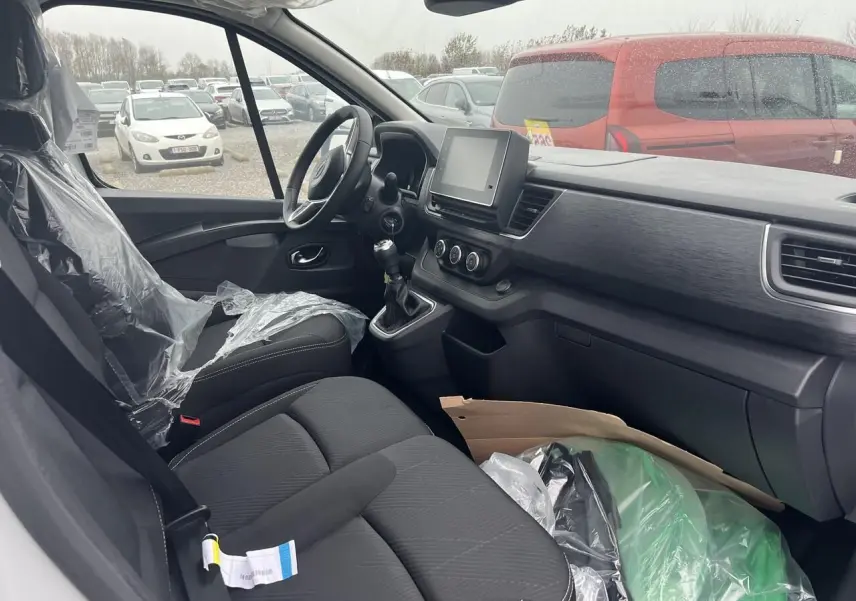 Intérieur côté conducteur du Nissan Primastar blanc 2025, montrant le tableau de bord et la console centrale avec boîte manuelle.
