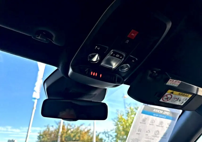 Vue intérieure du toit ouvrant et du panneau de commandes avec bouton SOS d'un Opel Mokka Electric gris 2025.