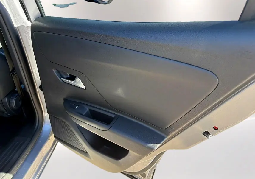 Vue rapprochée de la porte avant gauche grise de l’Opel Mokka Electric 156 gs avec poignée argentée et commande de vitre.