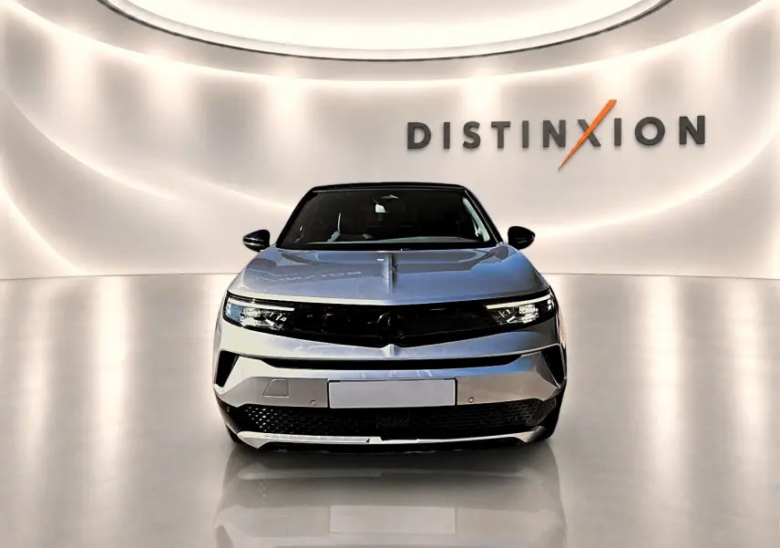 Vue frontale d'un Opel Mokka Electric 156 GS gris, avec calandre noire et éclairage LED moderne dans un showroom épuré.