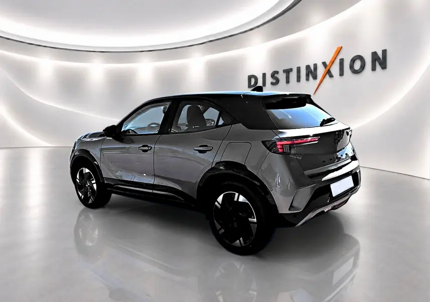 Opel Mokka Electric gris en 3/4 arrière droit, avec jantes alu noires et toit noir contrasté dans un showroom lumineux.