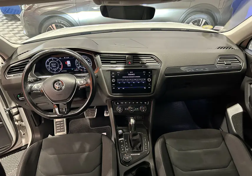 Vue intérieure avant du Volkswagen Tiguan Allspace 2018, tableau de bord noir avec écran tactile et volant multifonction.