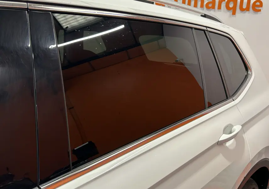 Vue latérale droite du Volkswagen Tiguan Allspace blanc avec vitres teintées et poignée de porte visible.