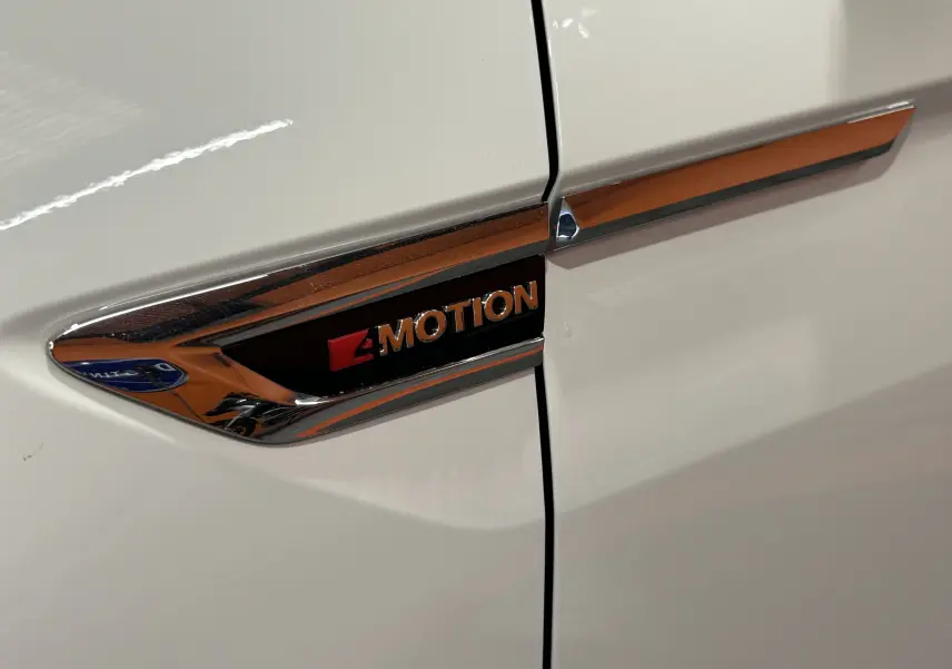 Gros plan sur l'emblème 4Motion chromé sur la portière blanche d'un Volkswagen Tiguan Allspace 2018.