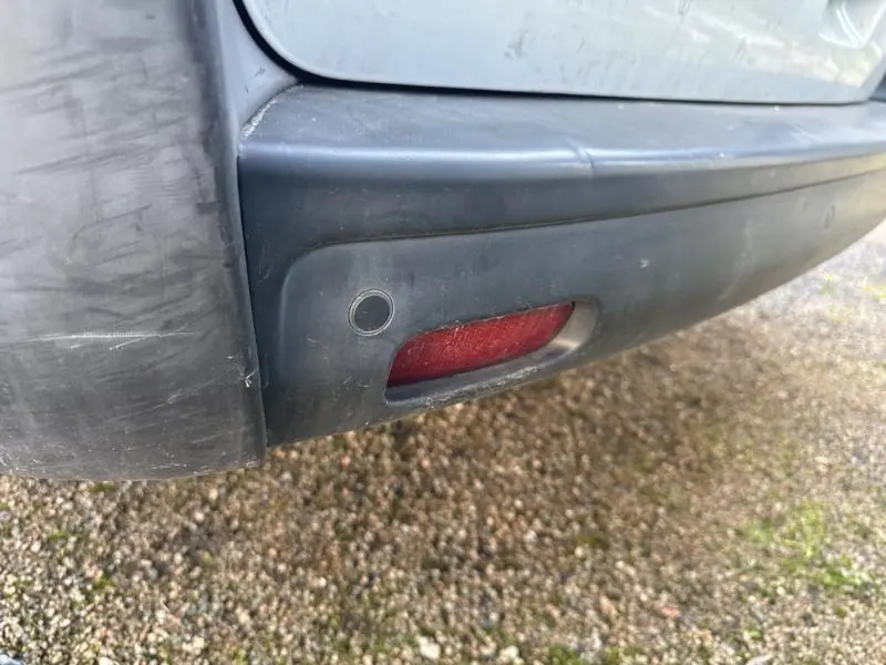 Gros plan sur le pare-chocs arrière noir avec feu de brouillard rouge du Citroën Jumpy blanc Banquise.