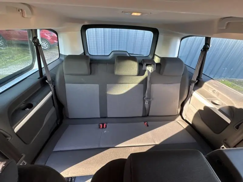 Vue intérieure arrière du Citroën Jumpy XL 9 places, montrant la banquette tissu gris avec ceintures et vitres latérales.