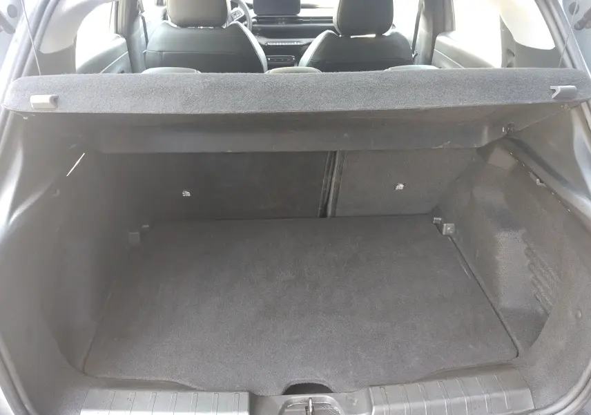 Vue intérieure du coffre spacieux du Jeep Avenger eHYBRID 110ch gris, avec banquette arrière et tablette cache-bagages visibles.