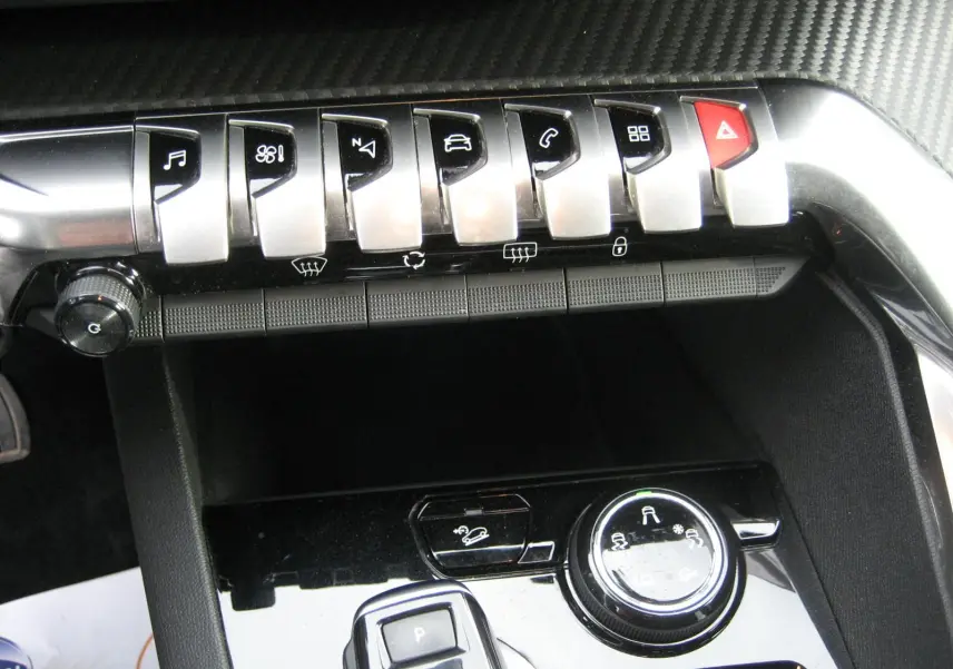 Gros plan sur la console centrale noire du Peugeot 3008 2020 avec boutons de commande et molette de réglage.